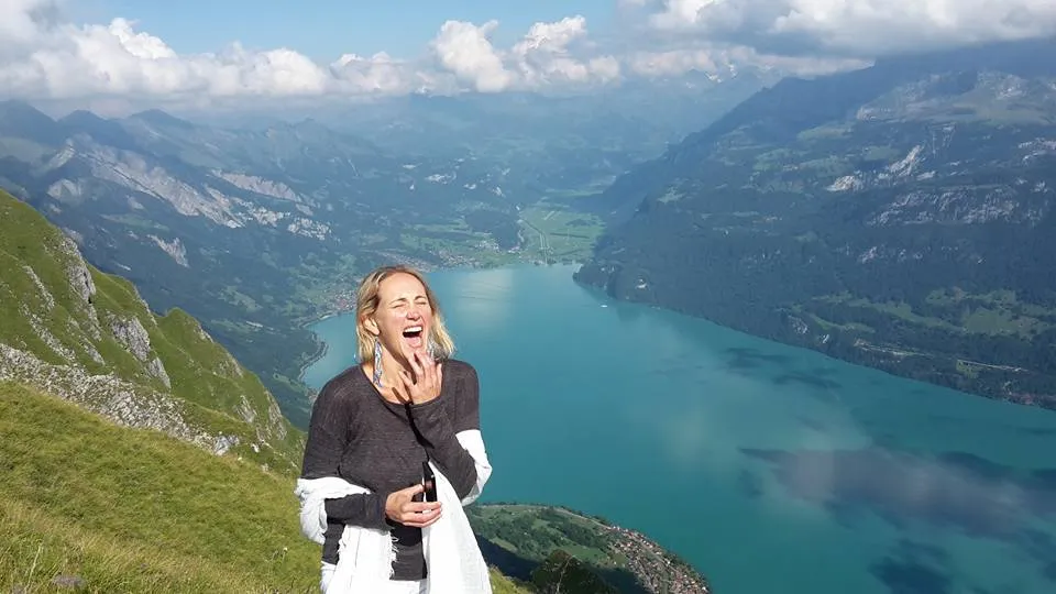 Samantha Claire laughing on a mountain above an alpine lake