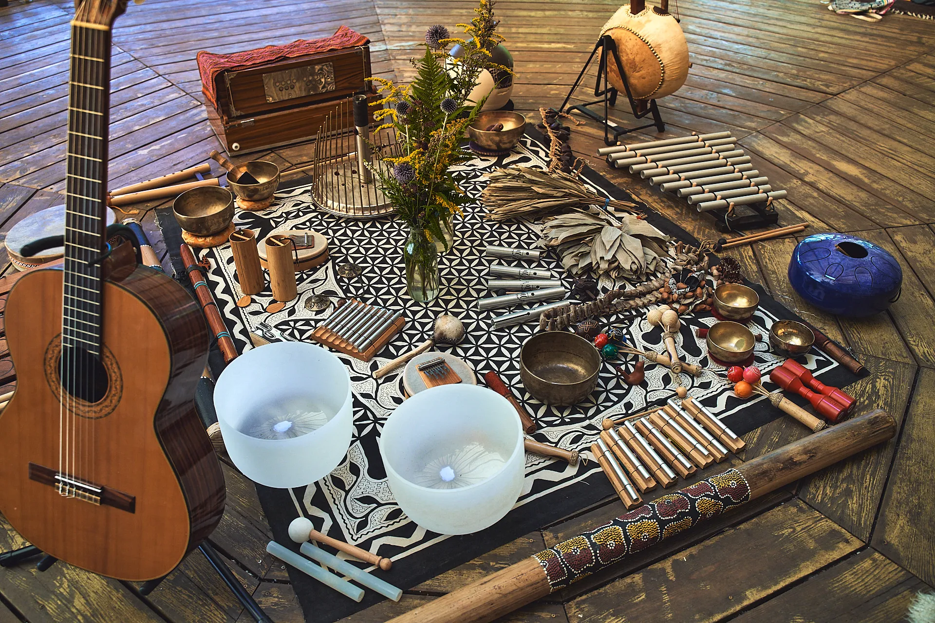 Sound healing instruments including singing bowls, chimes, guitar and didgeridoo, laid out for a session